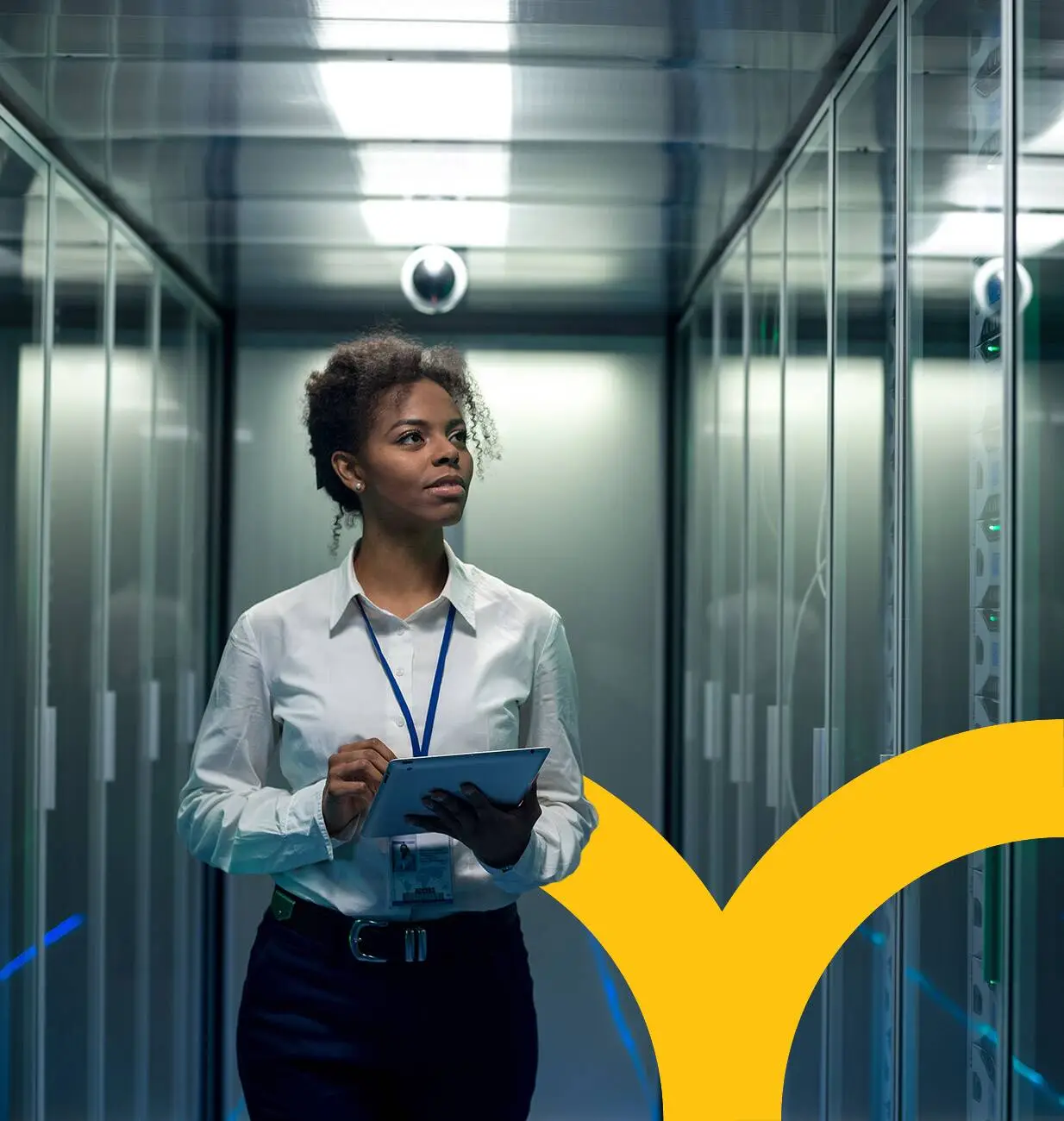 Woman with clipboard walking down aisle of tall servers.