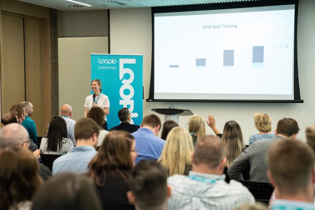 A woman stands in front of a crowd delivering a session at Loopicon 2019.