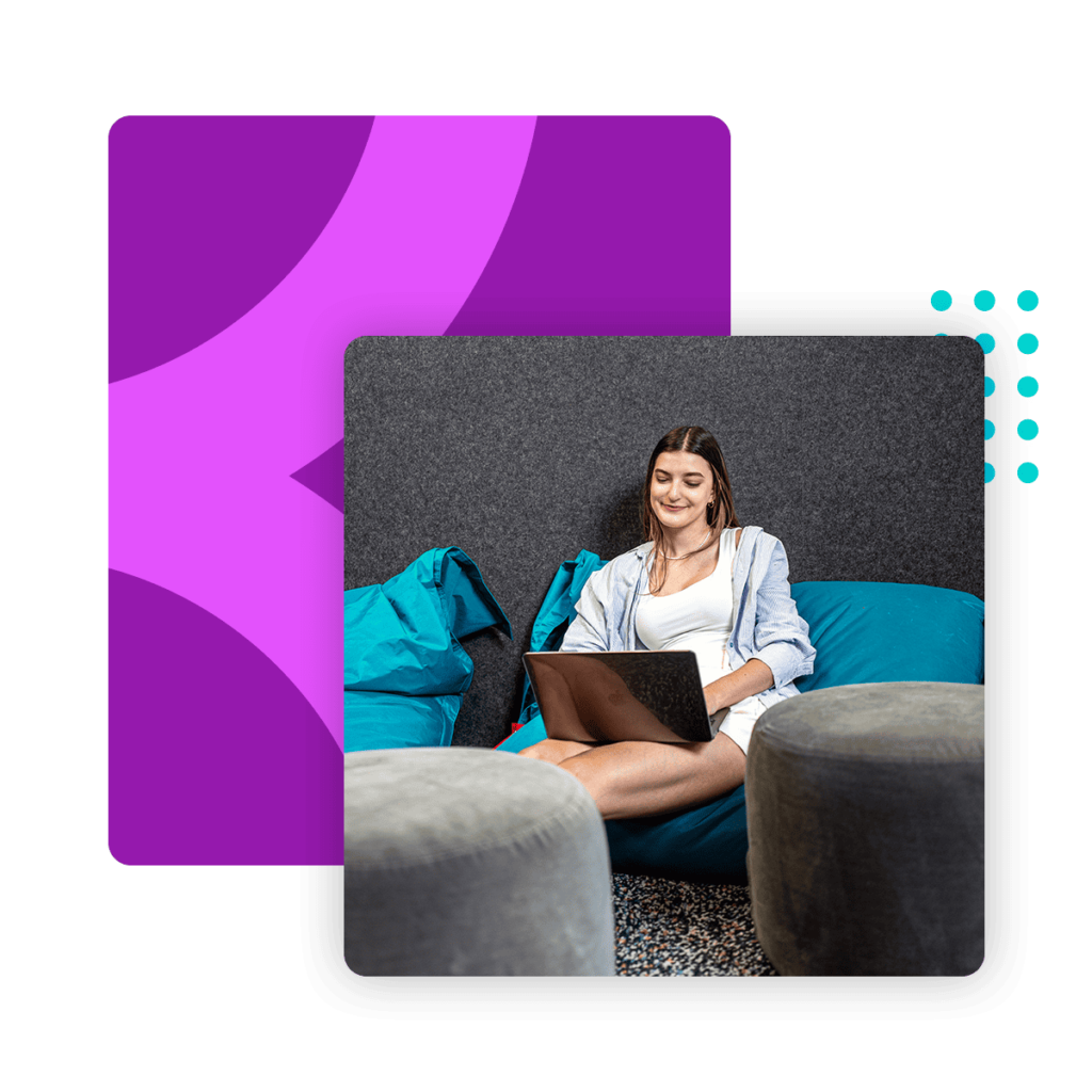 A Loopio employee is sitting on a bean bag at Loopio's office and working on her laptop.