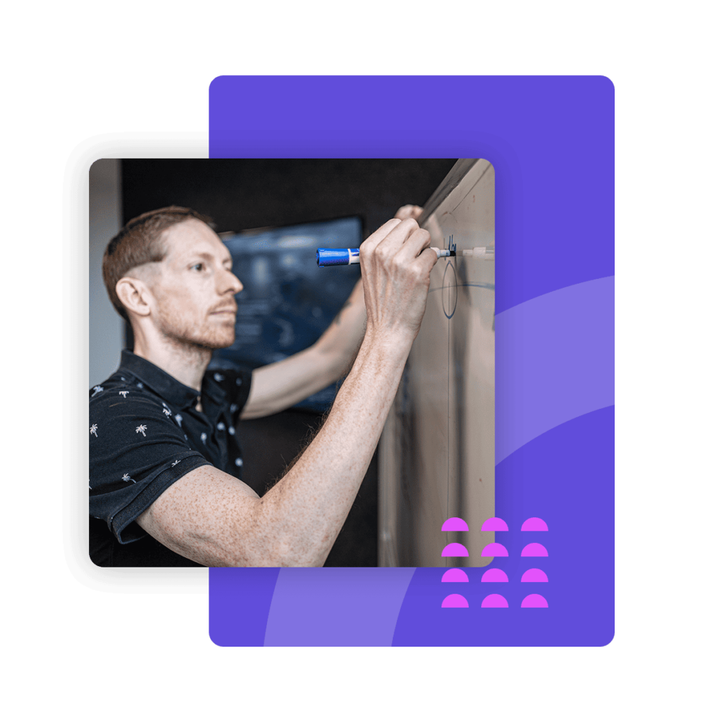 A Loopio employee is writing on a white board in the boardroom.